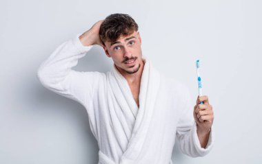 Genç ve yakışıklı bir adam stresli, endişeli ya da korkmuş hissediyor. Elleri başının üstünde. diş fırçası kavramı