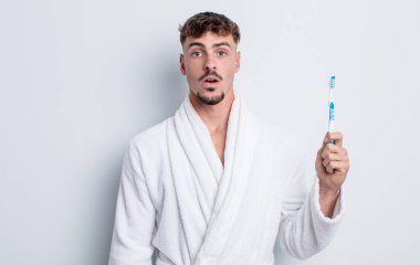 Genç ve yakışıklı bir adam çok şaşırmış ya da şaşkın görünüyor. diş fırçası kavramı