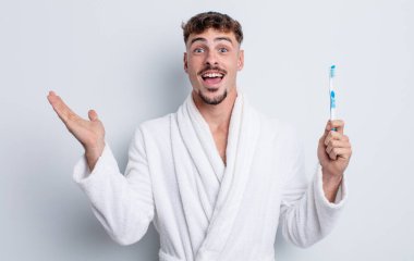 Genç yakışıklı adam kendini mutlu hissediyor ve inanılmaz bir şeye hayret ediyor. diş fırçası kavramı