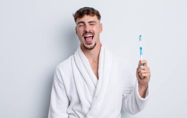 Genç, yakışıklı, neşeli ve asi tavırlı, şaka yapan ve dilini dışarı çıkaran bir adam. diş fırçası kavramı