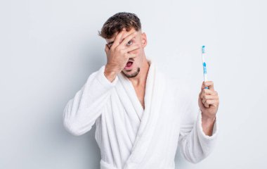 Genç, yakışıklı adam şok olmuş, korkmuş ya da korkmuş görünüyor. diş fırçası kavramı