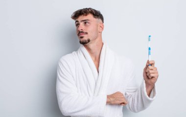 Genç yakışıklı adam omuz silkiyor, kafası karışık ve kararsız. diş fırçası kavramı