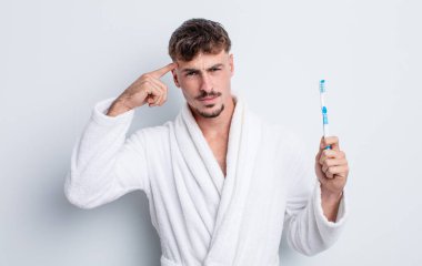 Genç yakışıklı adam kafası karışık ve şaşkın hissediyor, deli olduğunu gösteriyor. diş fırçası kavramı