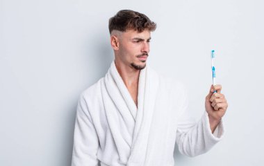 Genç ve yakışıklı bir adam üzgün, üzgün ya da kızgın hissediyor ve yan tarafa bakıyor. diş fırçası kavramı