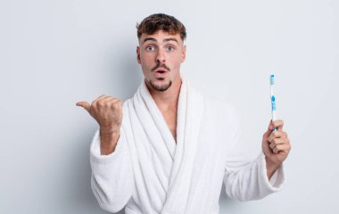 İnanamadığı için şaşırmış genç ve yakışıklı bir adam. diş fırçası kavramı