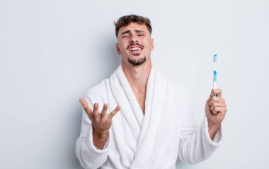 Genç yakışıklı adam umutsuz, sinirli ve stresli görünüyor. diş fırçası kavramı