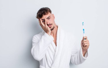 Genç yakışıklı bir adam bıkkın, hayal kırıklığına uğramış ve yorucu bir geceden sonra uykulu hissediyor. diş fırçası kavramı