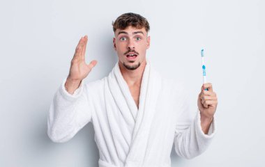 Genç yakışıklı adam ellerini havaya kaldırarak çığlık atıyor. diş fırçası kavramı