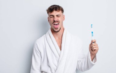 Genç ve yakışıklı bir adam tiksinmiş ve sinirlenmiş hissediyor ve dilini dışarı çıkarıyor. diş fırçası kavramı