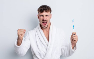 Genç yakışıklı adam sinirli bir ifadeyle agresif bir şekilde bağırıyor. diş fırçası kavramı