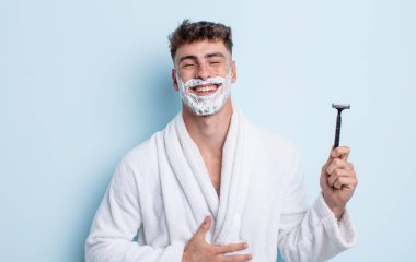 Genç yakışıklı bir adam komik bir şakaya yüksek sesle gülüyor. traş konsepti