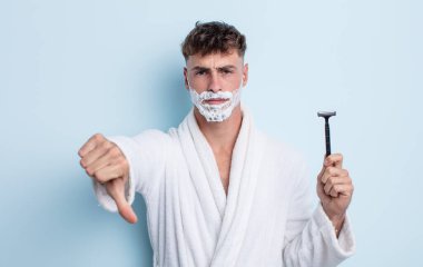 Genç ve yakışıklı bir adam kendini kötü hissediyor, baş parmağını kaldırıyor. traş konsepti