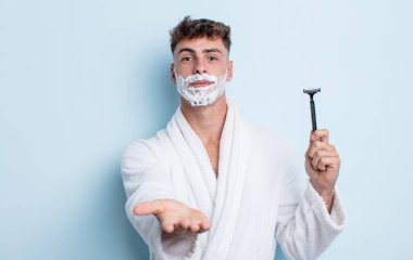 Genç ve yakışıklı bir adam arkadaşça gülümsüyor ve bir konsept sunuyor. traş konsepti