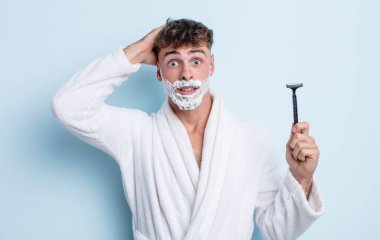 Genç ve yakışıklı bir adam stresli, endişeli ya da korkmuş hissediyor. Elleri başının üstünde. traş konsepti