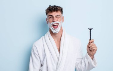 Genç, yakışıklı, neşeli ve asi tavırlı, şaka yapan ve dilini dışarı çıkaran bir adam. traş konsepti