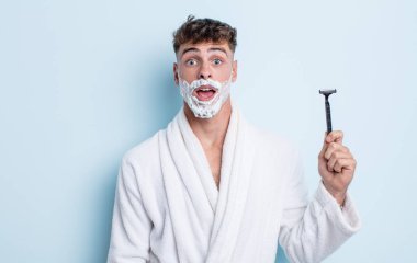 Genç ve yakışıklı bir adam çok şaşırmış ya da şaşkın görünüyor. traş konsepti