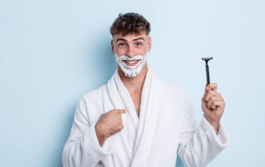 Genç ve yakışıklı bir adam mutlu hissediyor ve heyecanla kendini işaret ediyor. traş konsepti