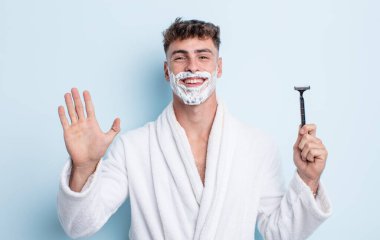 Genç yakışıklı adam mutlu bir şekilde gülümsüyor, el sallıyor, sizi selamlıyor ve selamlıyor. traş konsepti