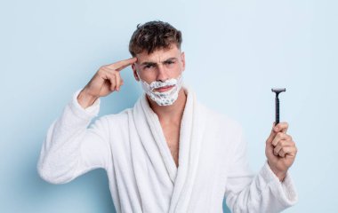 Genç yakışıklı adam kafası karışık ve şaşkın hissediyor, deli olduğunu gösteriyor. traş konsepti