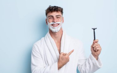 Genç yakışıklı adam neşeyle gülümsüyor, mutlu hissediyor ve bir tarafı işaret ediyor. traş konsepti