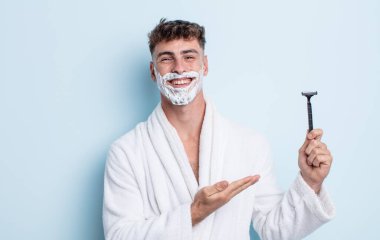 Genç yakışıklı adam neşeyle gülümsüyor, mutlu hissediyor ve bir konsept gösteriyor. traş konsepti