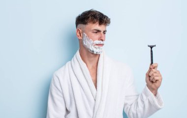 Genç ve yakışıklı bir adam üzgün, üzgün ya da kızgın hissediyor ve yan tarafa bakıyor. traş konsepti