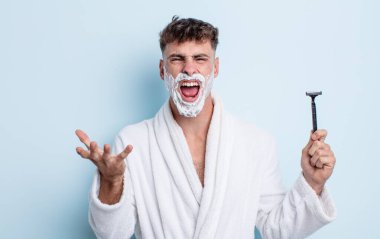 Genç ve yakışıklı bir adam sinirli, sinirli ve sinirli görünüyor. traş konsepti