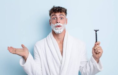 Genç, yakışıklı adam şaşırmış ve şok olmuş görünüyor. Çenesi düşmüş, elinde bir nesne var. traş konsepti