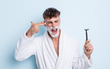 Genç yakışıklı adam mutsuz ve stresli görünüyor, intihar jesti silah işareti yapıyor. traş konsepti