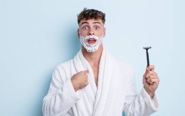 Şok olmuş ve ağzı açık, kendini işaret eden genç ve yakışıklı bir adam. traş konsepti