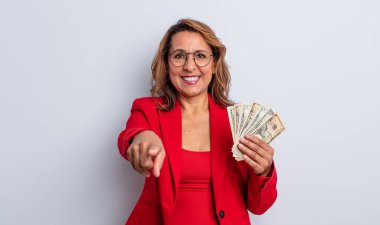 Güzel orta yaşlı bir kadın kamerayı işaret ederek seni seçiyor. Dolar banknotları konsepti