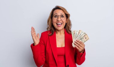 Oldukça orta yaşlı bir kadın inanılmaz bir şey karşısında mutlu ve şaşkın hissediyor. Dolar banknotları konsepti