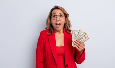 Güzel, orta yaşlı bir kadın çok şaşırmış ya da şaşkın görünüyor. Dolar banknotları konsepti