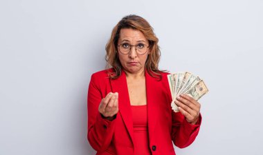 Güzel orta yaşlı bir kadın kapiş ya da para hareketi yapıyor, sana ödemeni söylüyor. Dolar banknotları konsepti