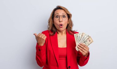 İnançsızlığa şaşırmış orta yaşlı bir kadın. Dolar banknotları konsepti