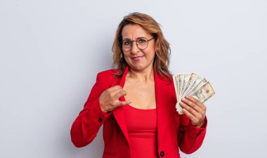Güzel, orta yaşlı bir kadın kibirli, başarılı, pozitif ve gururlu görünüyor. Dolar banknotları konsepti