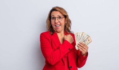 Orta yaşlı güzel bir kadın kendini mutlu hissediyor ve bir meydan okumayla yüzleşiyor ya da kutluyor. Dolar banknotları konsepti