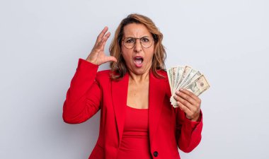 Orta yaşlı güzel bir kadın ellerini havaya kaldırarak çığlık atıyor. Dolar banknotları konsepti