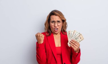 Oldukça orta yaşlı bir kadın sinirli bir ifadeyle agresif bir şekilde bağırıyor. Dolar banknotları konsepti
