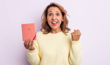 Oldukça orta yaşlı bir kadın şokta, gülüyor ve başarıyı kutluyor. ajanda kavramı