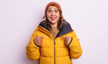 Oldukça orta yaşlı bir kadın mutlu hissediyor ve heyecanla kendini işaret ediyor. kış konsepti