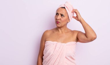 Güzel orta yaşlı bir kadın mutlu bir şekilde gülümsüyor ve hayal kuruyor ya da şüphe ediyor. güzellik ve duş konsepti