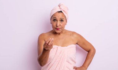 Güzel orta yaşlı bir kadın kapiş ya da para hareketi yapıyor, sana ödemeni söylüyor. güzellik ve duş konsepti