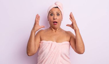 Orta yaşlı güzel bir kadın ellerini havaya kaldırarak çığlık atıyor. güzellik ve duş konsepti