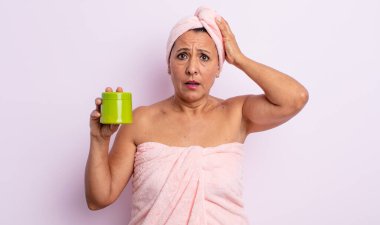 Oldukça orta yaşlı bir kadın stresli, endişeli ya da korkmuş, elleri başının üstünde. duş ve saç ürünü konsepti