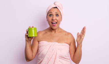 Oldukça orta yaşlı bir kadın inanılmaz bir şey karşısında mutlu ve şaşkın hissediyor. duş ve saç ürünü konsepti
