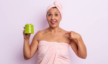 Oldukça orta yaşlı bir kadın mutlu hissediyor ve heyecanla kendini işaret ediyor. duş ve saç ürünü konsepti