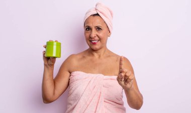 Güzel orta yaşlı kadın gururla gülümsüyor ve kendinden emin bir numara oluyor. duş ve saç ürünü konsepti