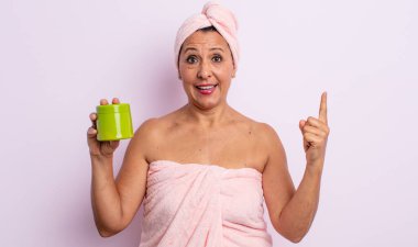 Güzel, orta yaşlı bir kadın bir fikri fark ettikten sonra mutlu ve heyecanlı bir dahi gibi hissediyor. duş ve saç ürünü konsepti