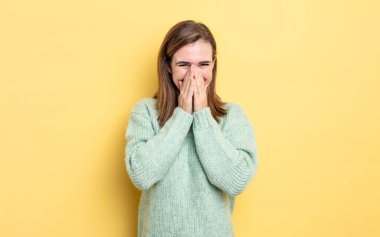 Genç ve güzel kız mutlu, neşeli, şanslı ve şaşkın görünüyor. İki eliyle ağzını kapatıyor.